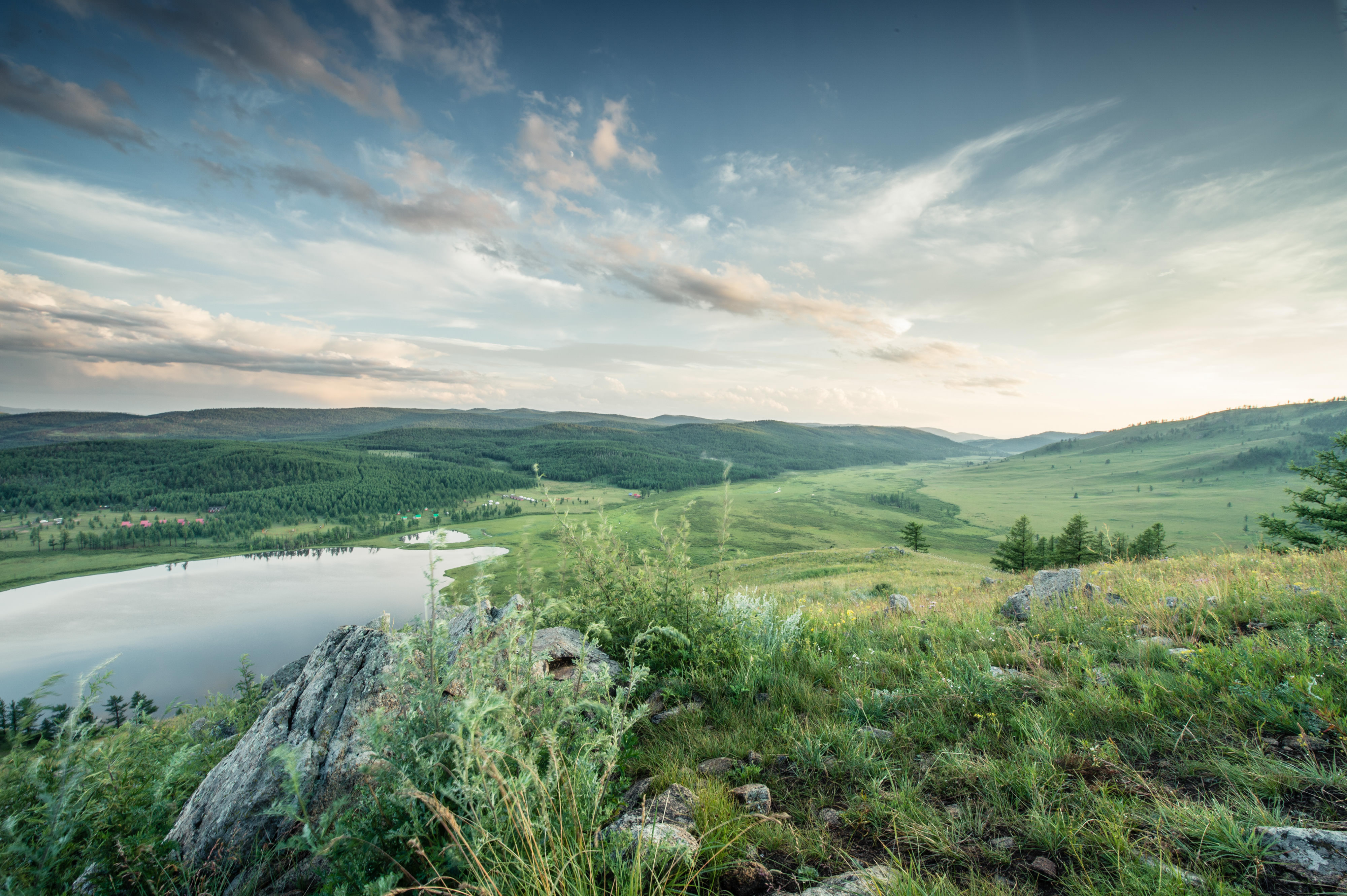 A view of a sweeping grassland landscape & cloudy sky.